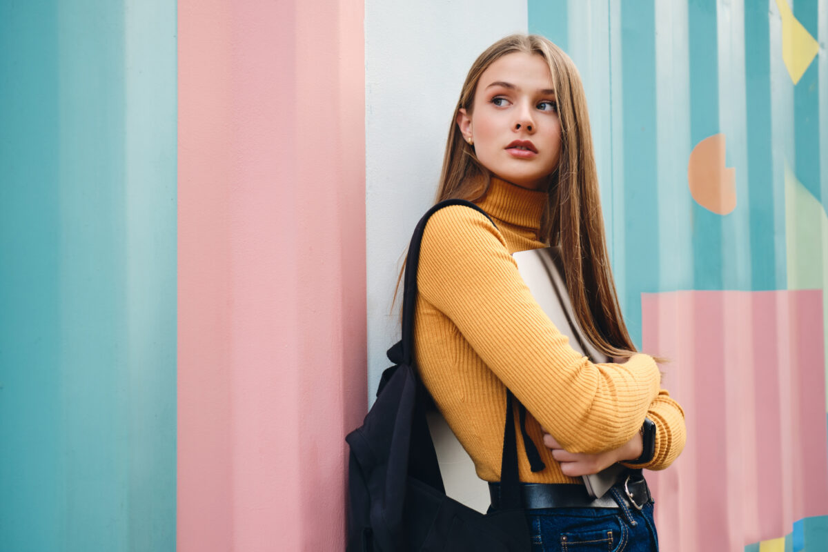 Beautiful casual student girl with laptop thoughtfully looking a