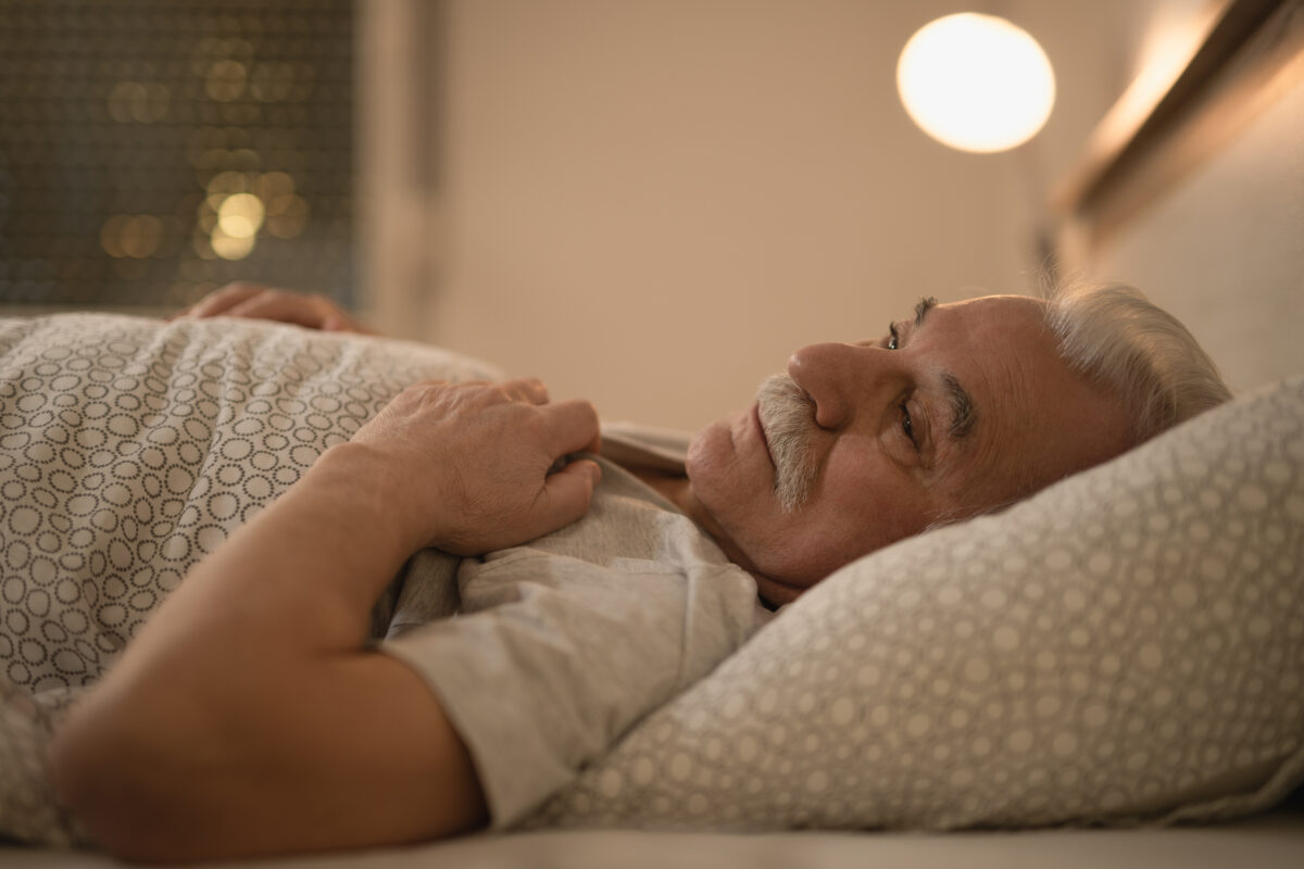 Distraught senior man thinking of something while lying down in